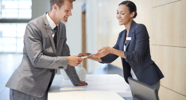 A handsome young man handing over a credit card to a woman